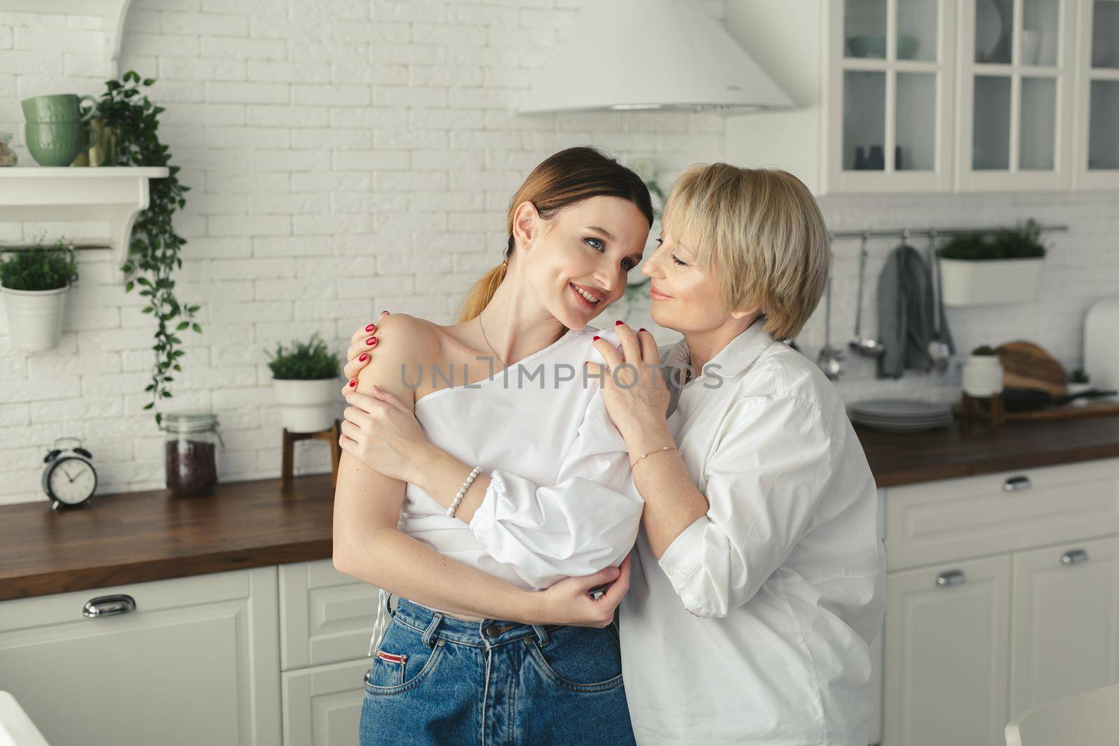 Happy loving older mature mother and grown daughter laughing embracing, caring smiling young woman embracing happy senior middle aged mom having fun at home spending time together