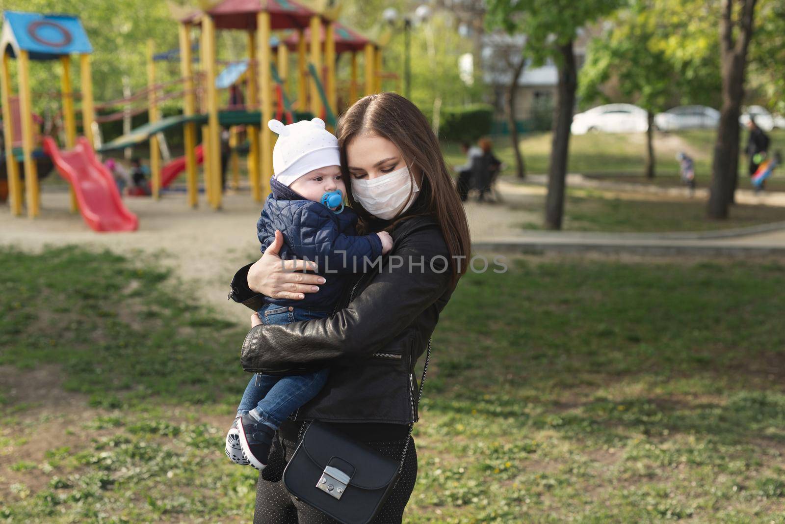 Young girl in a protective mask, hugs her little child. Covid-19