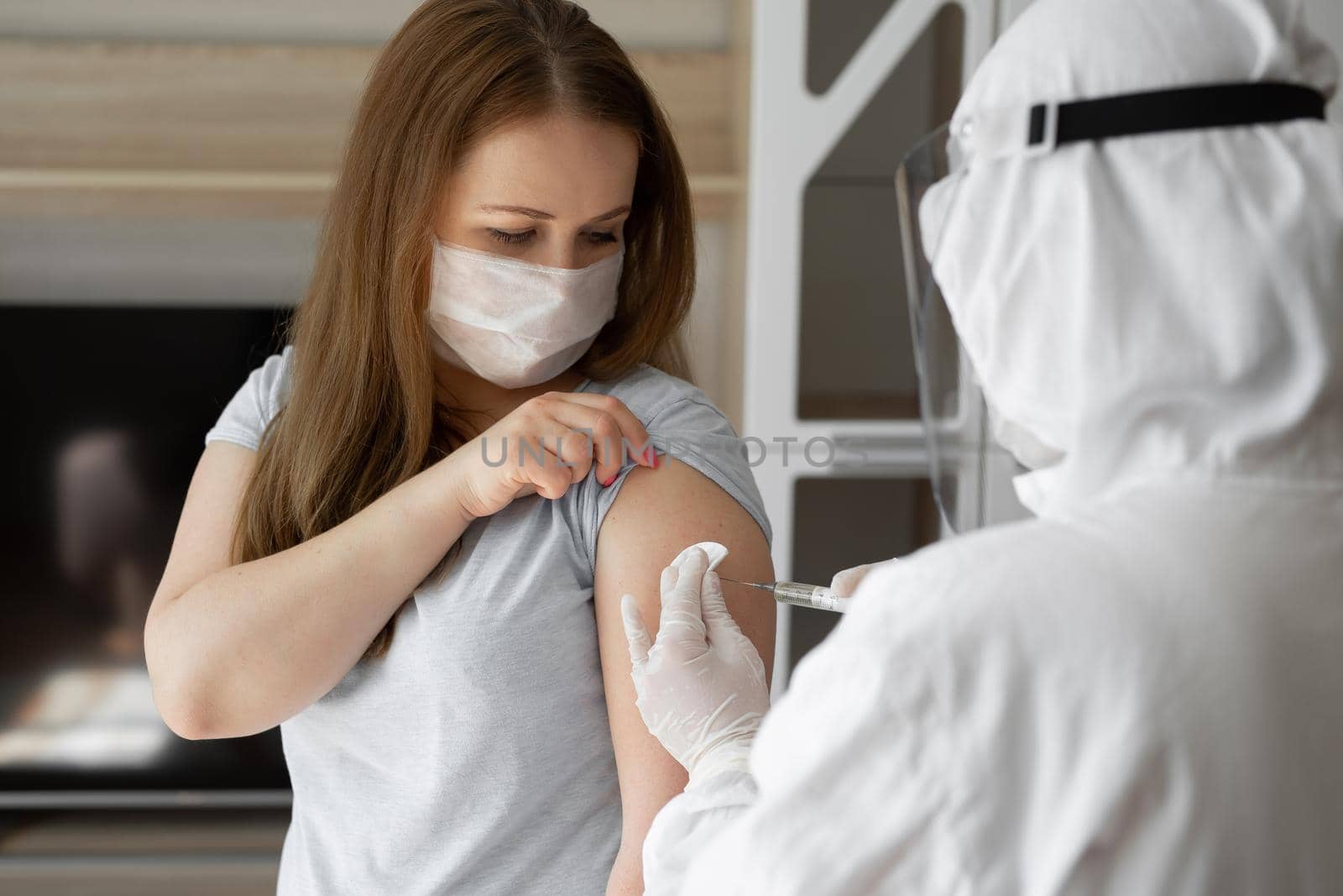 Doctor in personal protective suit or PPE inject vaccine shot to stimulating immunity of woman patient at risk of coronavirus infection. Coronavirus,covid-19 and vaccination concept.