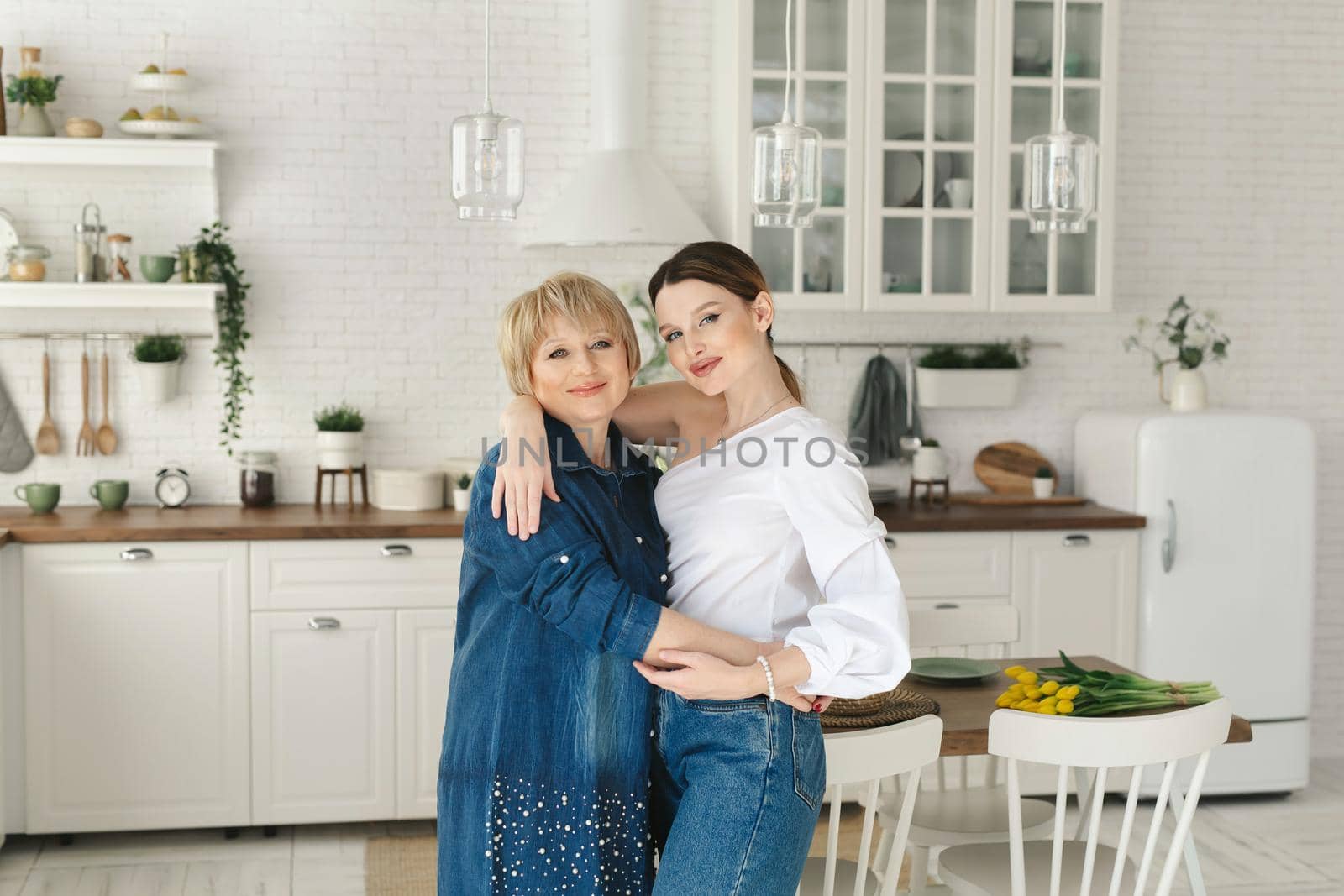 Close-up portrait of two nice attractive lovely tender cheerful women mom mommy adult daughter. Spending time day together in white light interior house flat apartment indoors by StudioPeace
