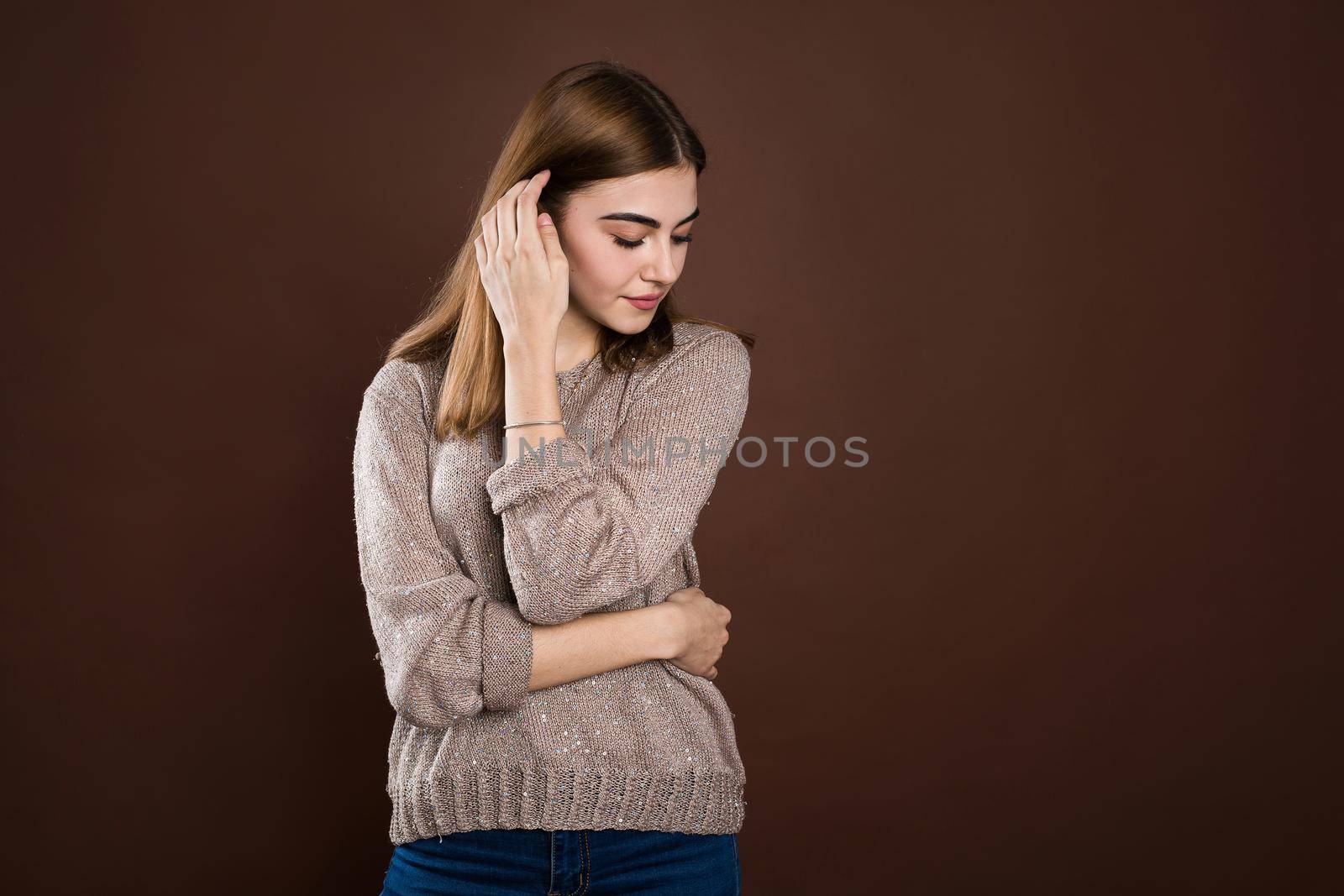Portrait of a beautiful girl in a sweater on a brown background. by StudioPeace