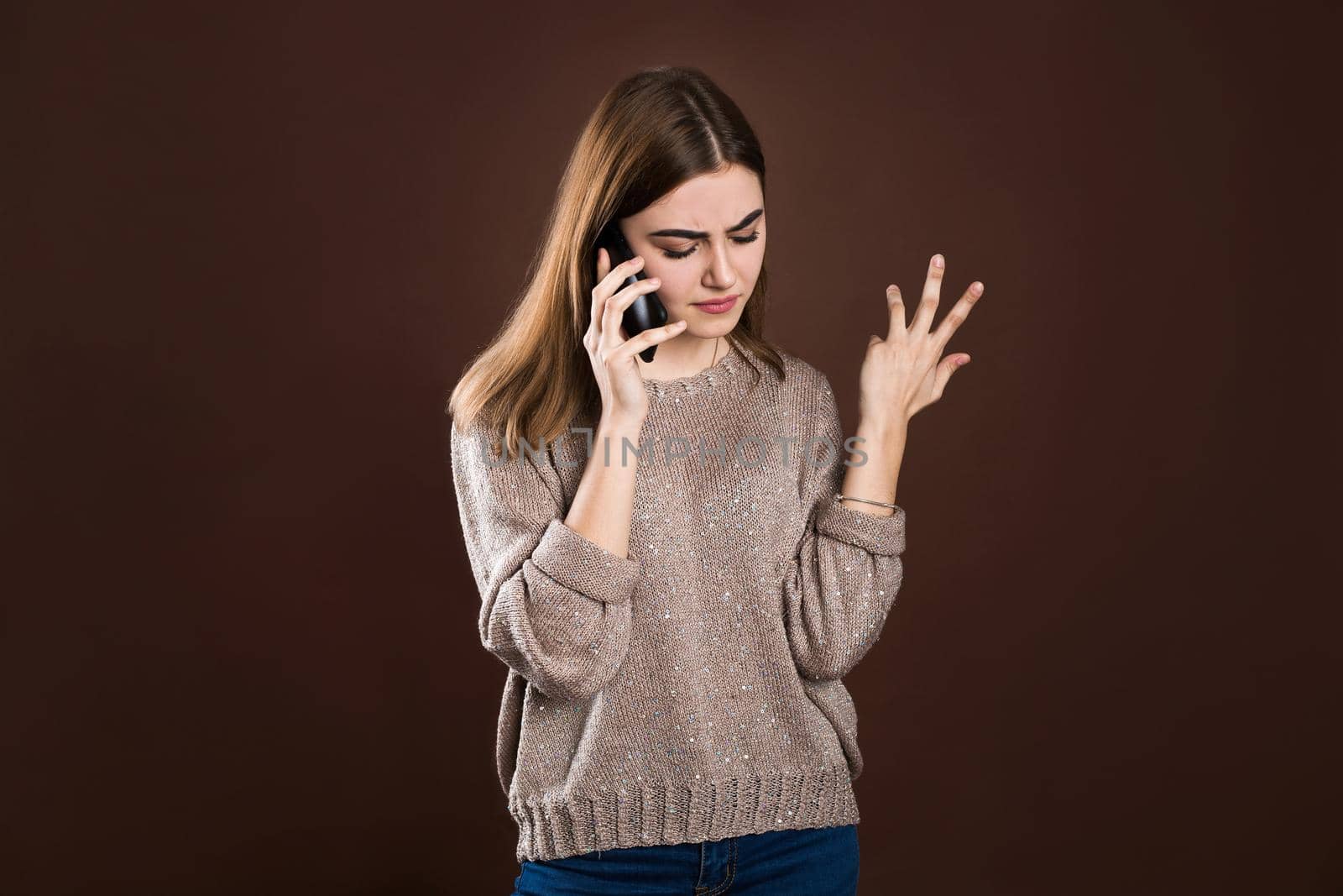 A girl swears on the phone on a brown background. by StudioPeace