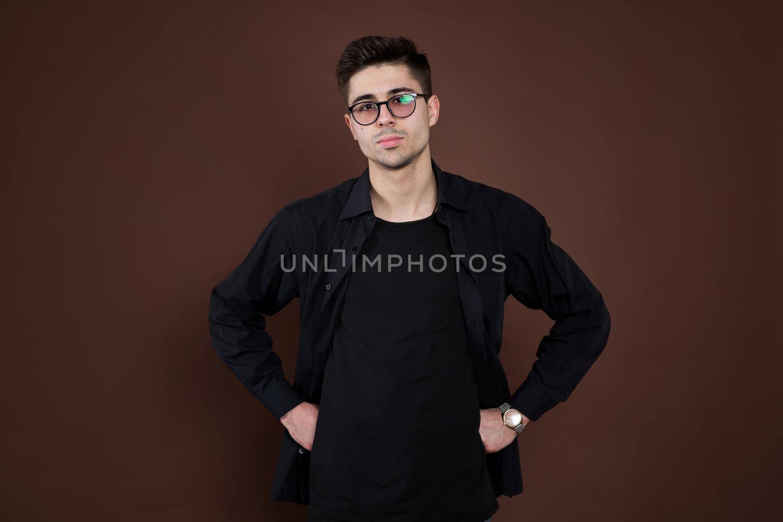 Young man in depression. Stylish male student wears round spectacles, has trendy hairstyle, looks confidently, isolated over brown background. People and human expressions. by StudioPeace