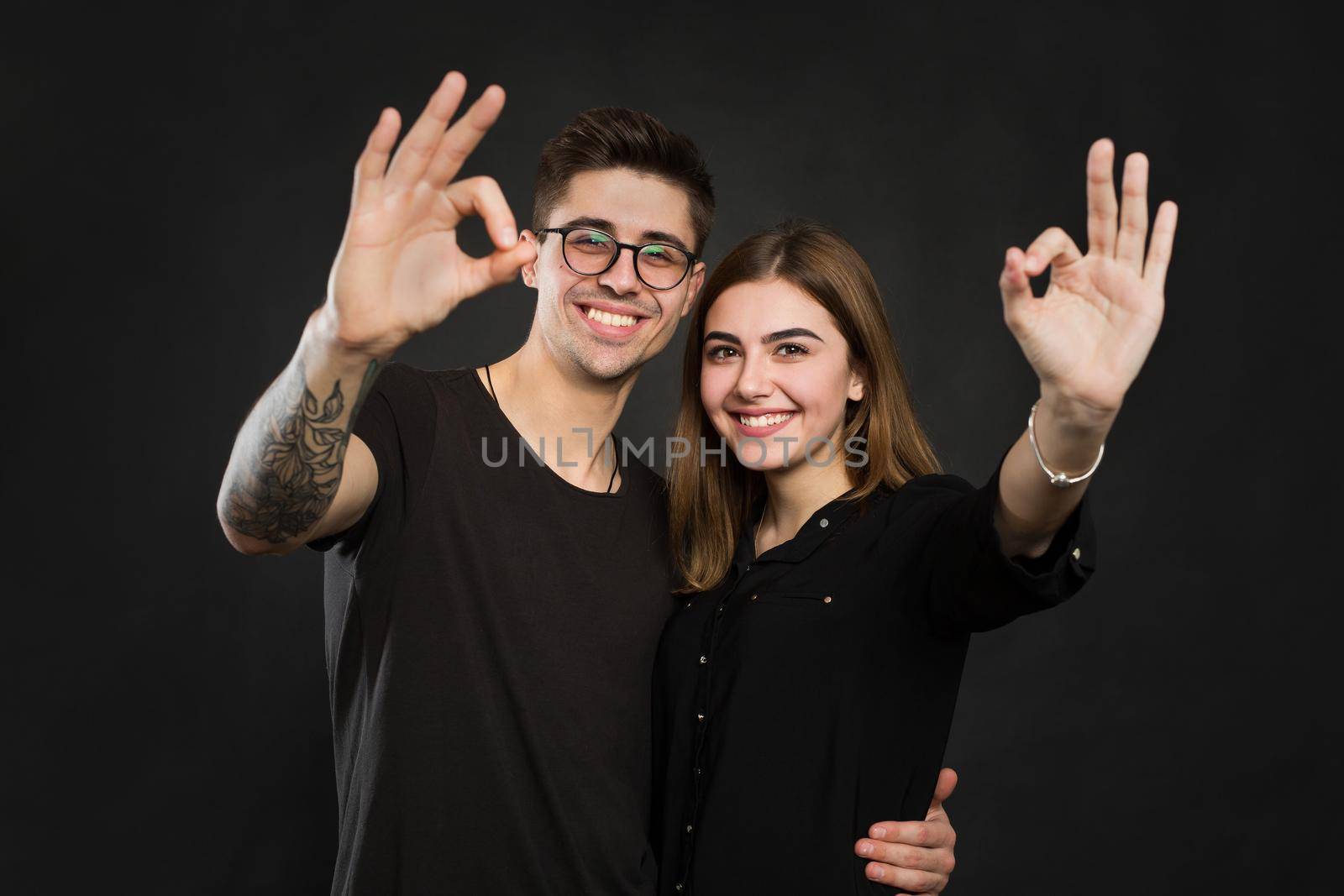 Couple making OK sign on black background