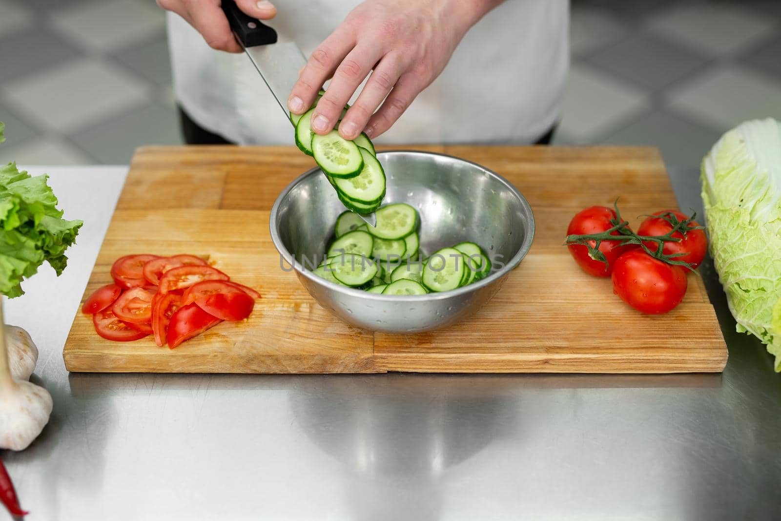 Chef in the kitchen cuts fresh and delicious vegetables for a vegetable salad