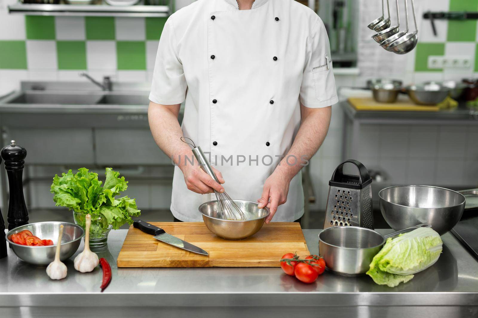 Chef whips eggs with his hands in a bowl to make an omelet with vegetables