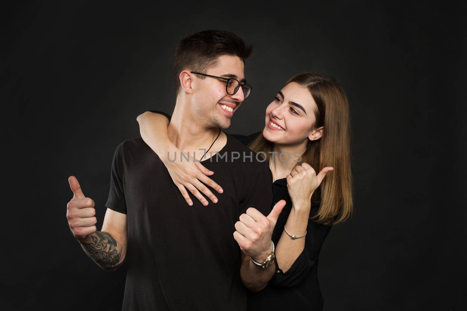 Happy couple love excited smiling holding thumb up gesture, beautiful young man and woman smile looking at camera, isolated over black background