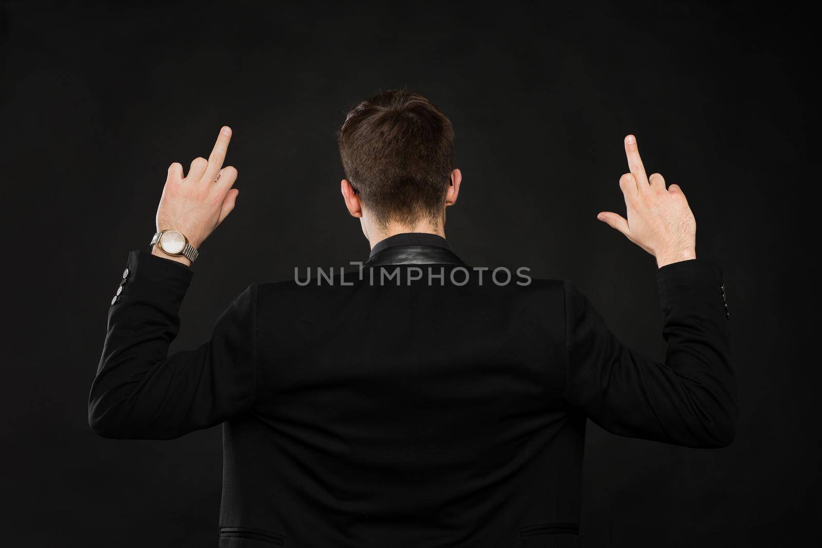 Handsome young man showing middle finger, insult sign on black background. by StudioPeace