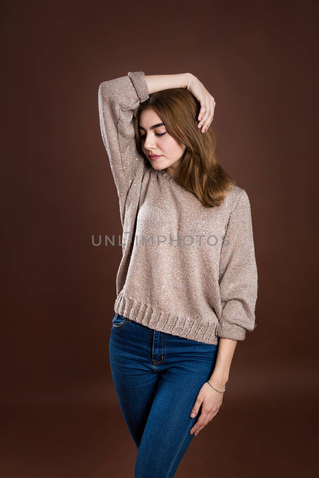 Portrait of a beautiful girl in a sweater on a brown background