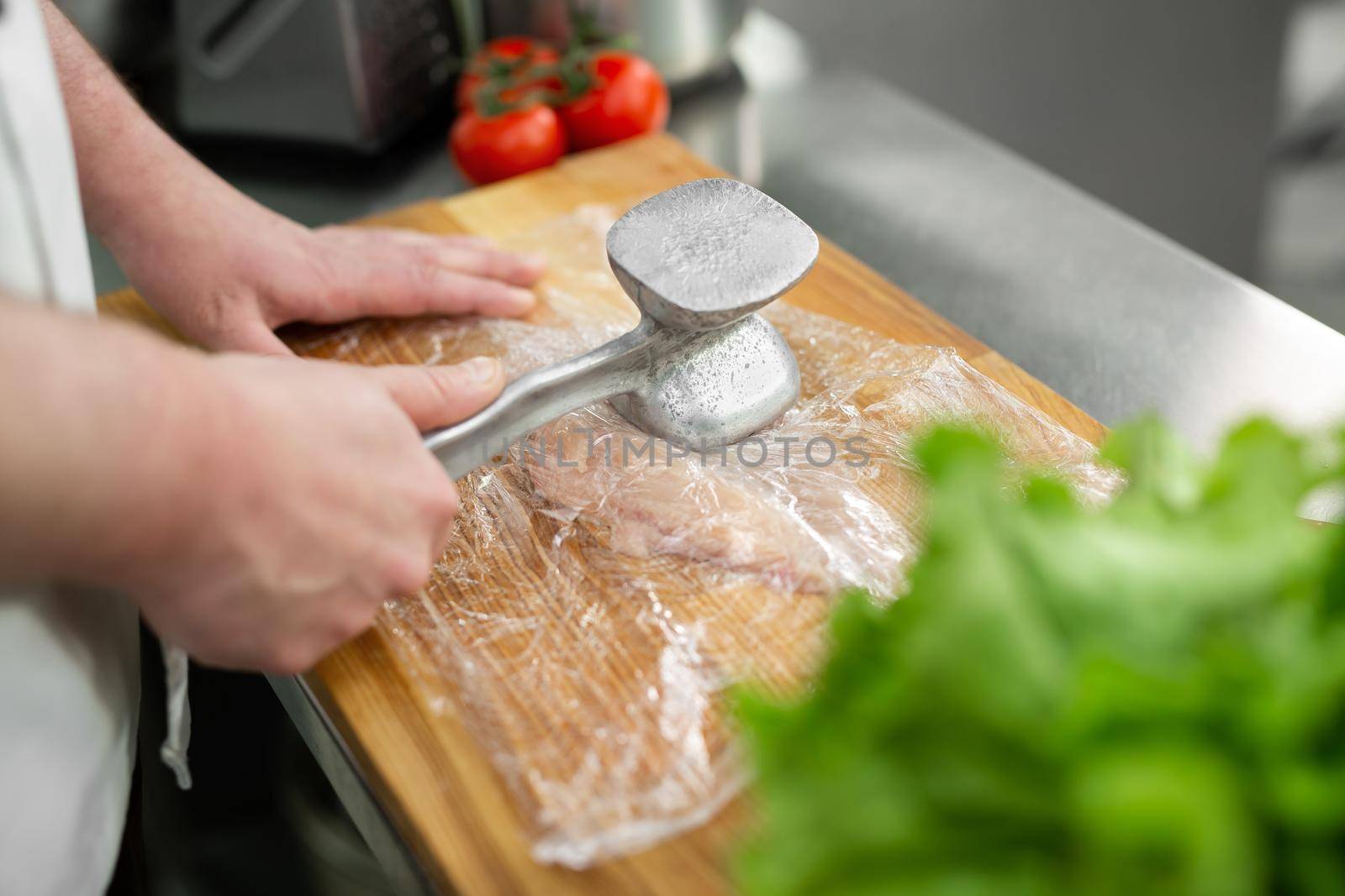 Cook beating a chicken breast with a hammer, close-up. Diet, healthy low-calorie food, weight loss concept