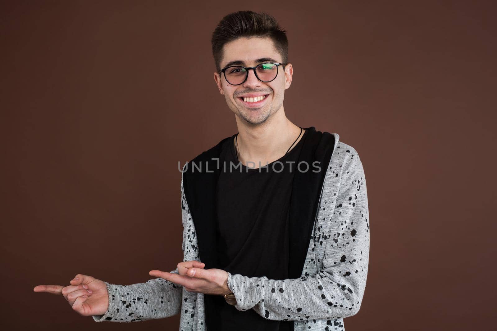 Portrait of a smiling man pointing finger away isolated on a brown background