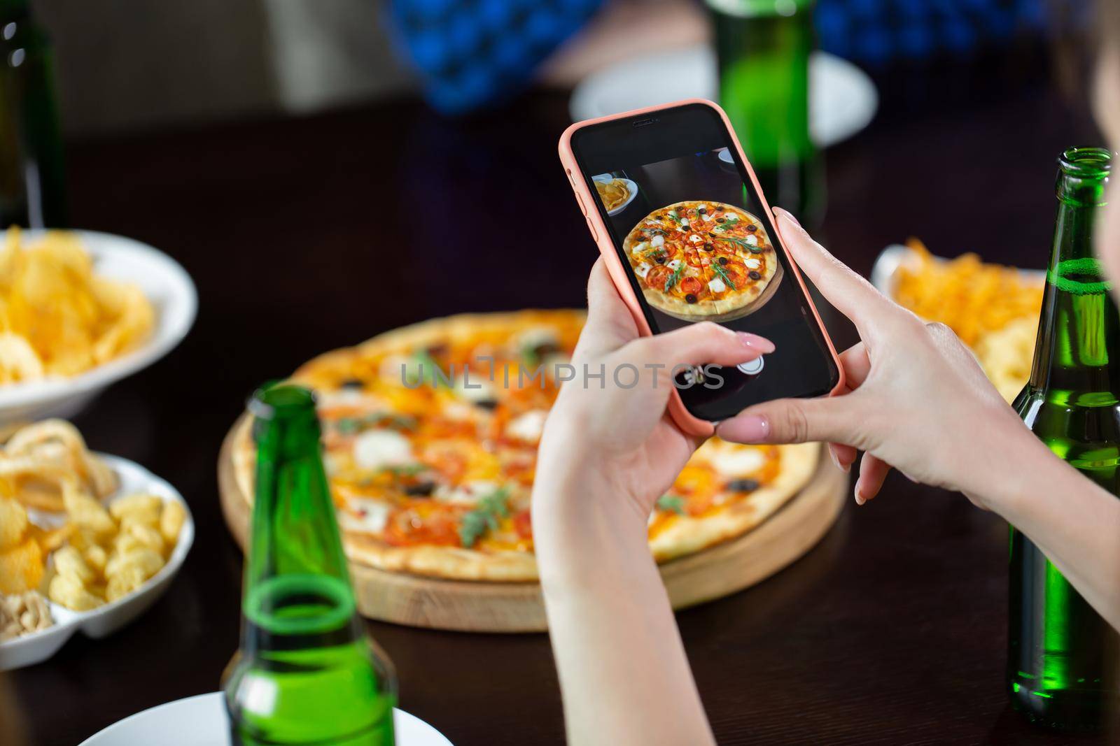 Woman taking photo of pizza with smart phone. by StudioPeace