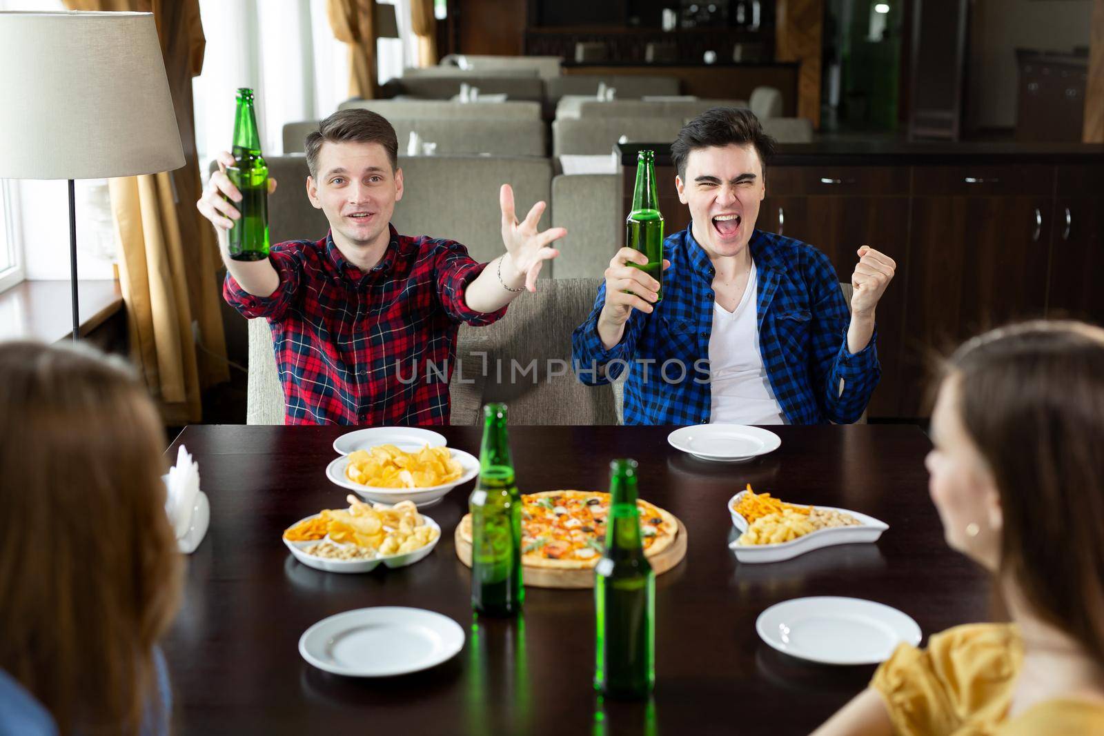 Young men drink beer, eat pizza and cheering for football