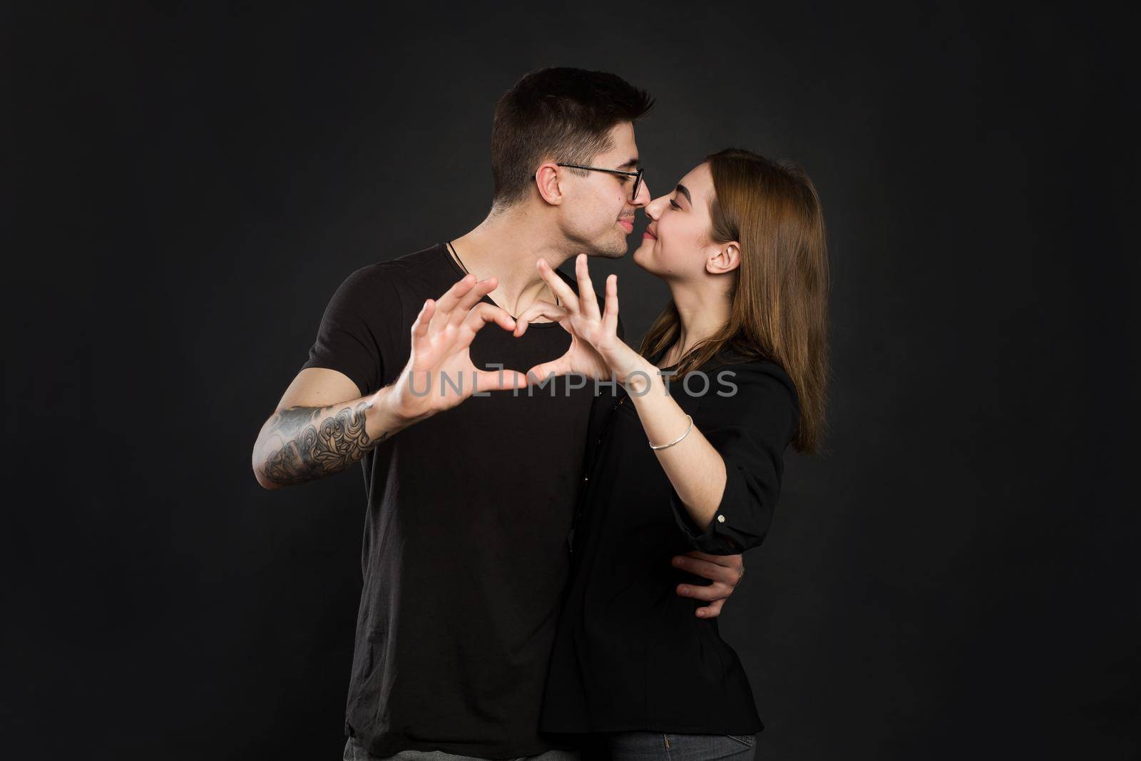 Happy couple in love showing heart with their fingers. Closeup of couple making heart shape with hands.