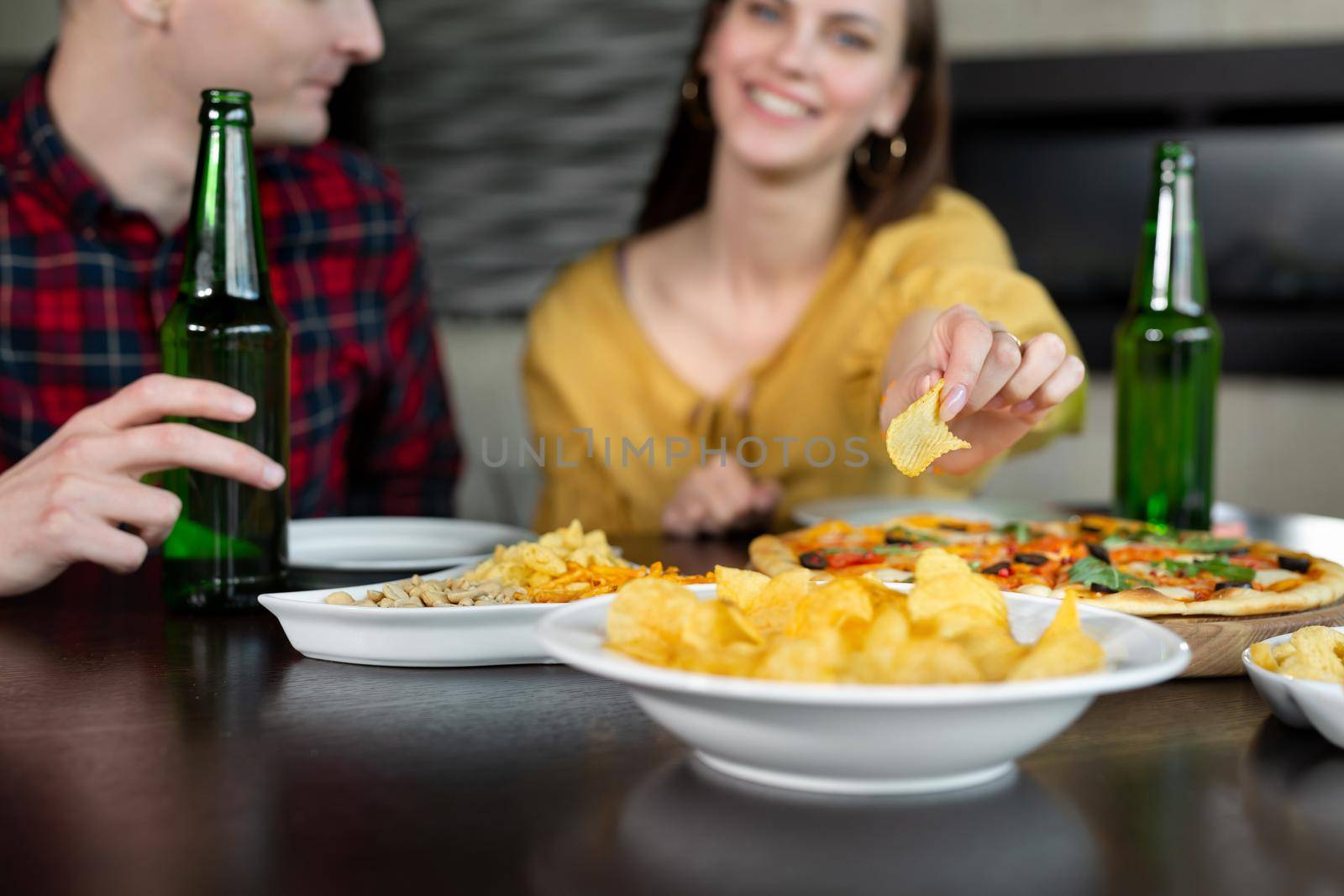 Woman eats chips and drinks beer with her boyfriend