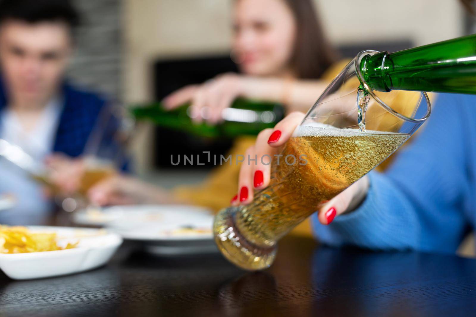 Girl pours beer from a bottle into a glass