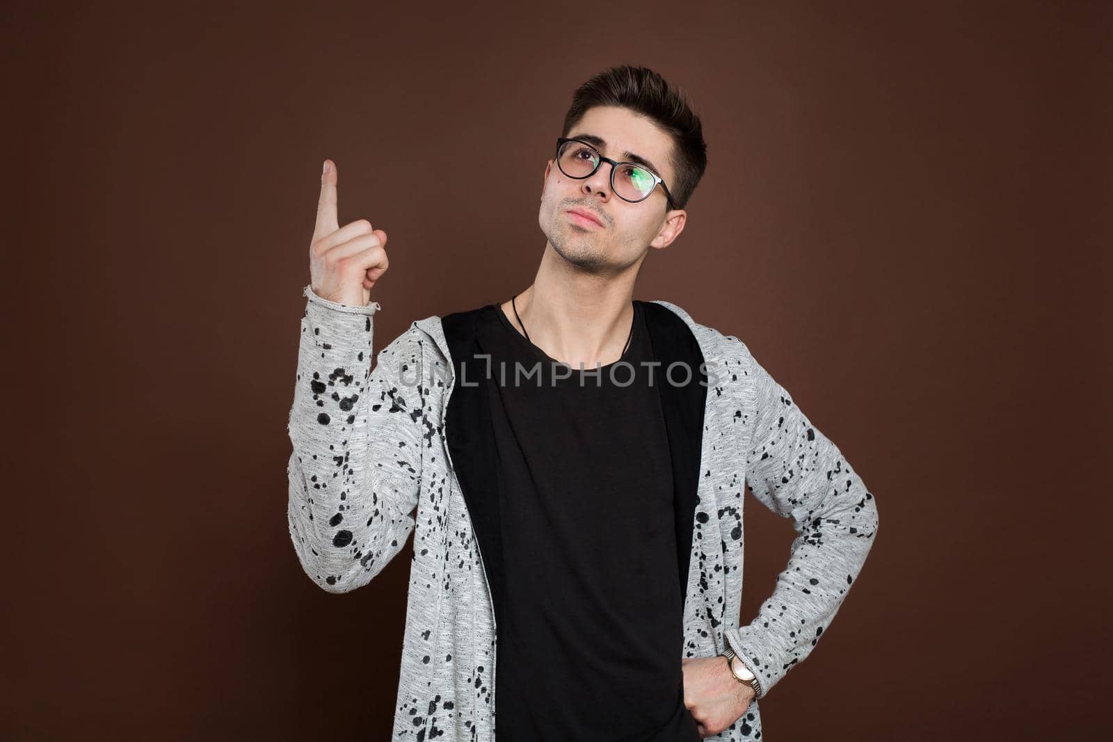 Happy cheerful young guy gesturing up with fingers