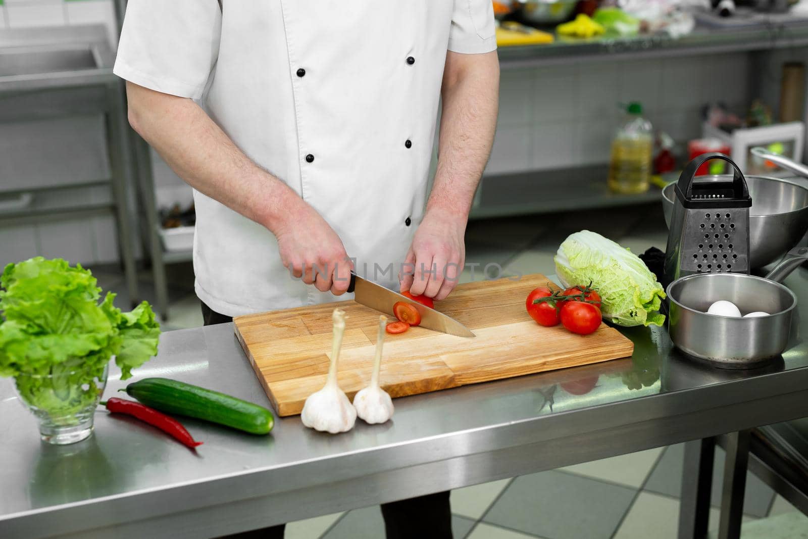 Chef in the kitchen cuts fresh and delicious vegetables for a vegetable salad. by StudioPeace