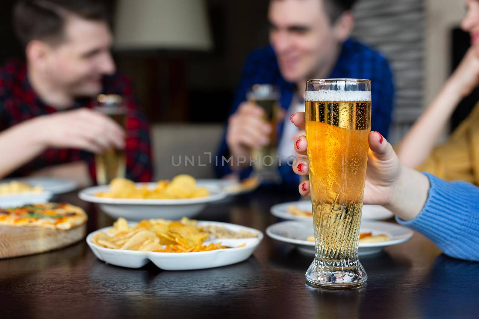 Girl holds a glass of beer in the foreground