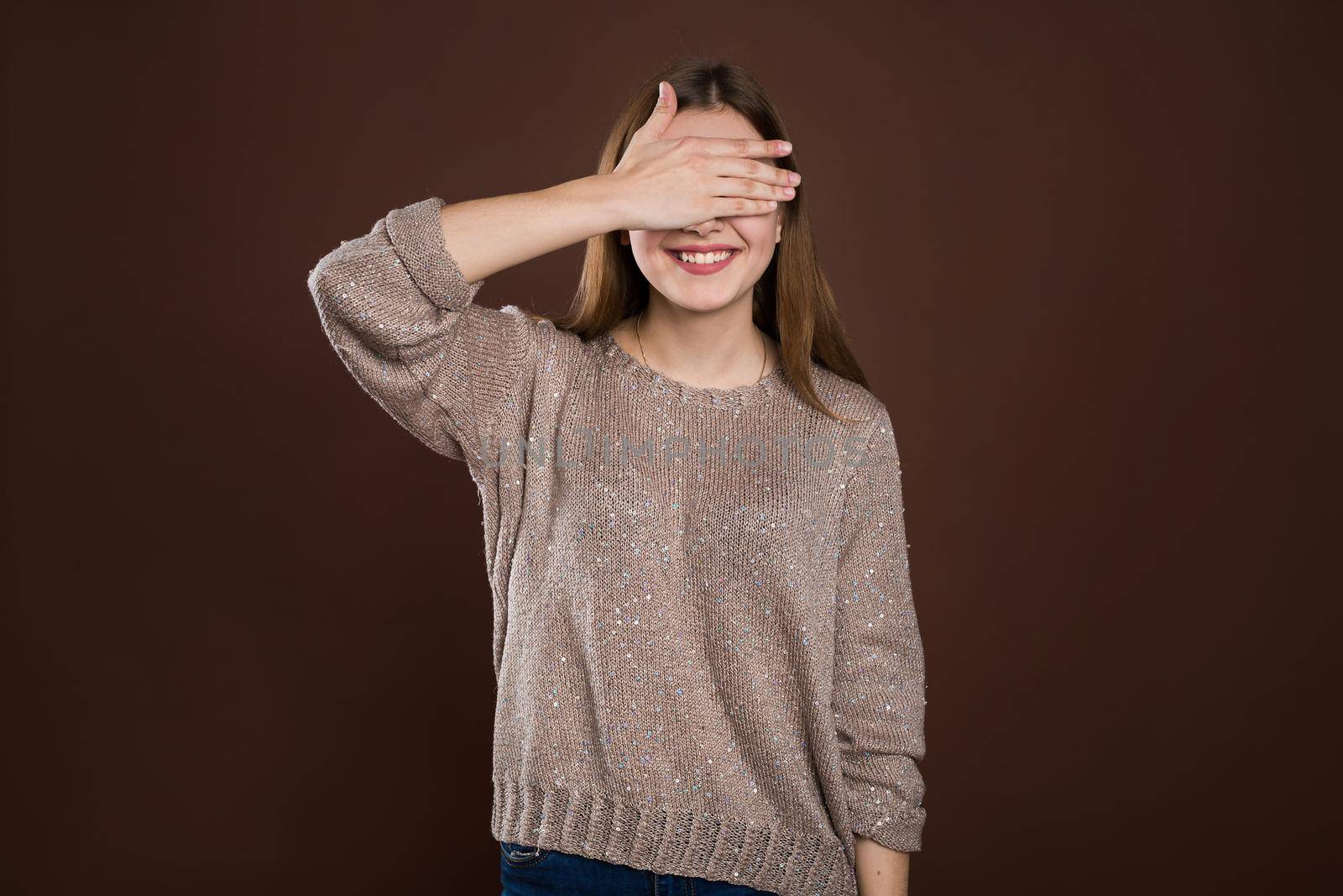 smiley woman covering her eyes by hands over brown background. by StudioPeace