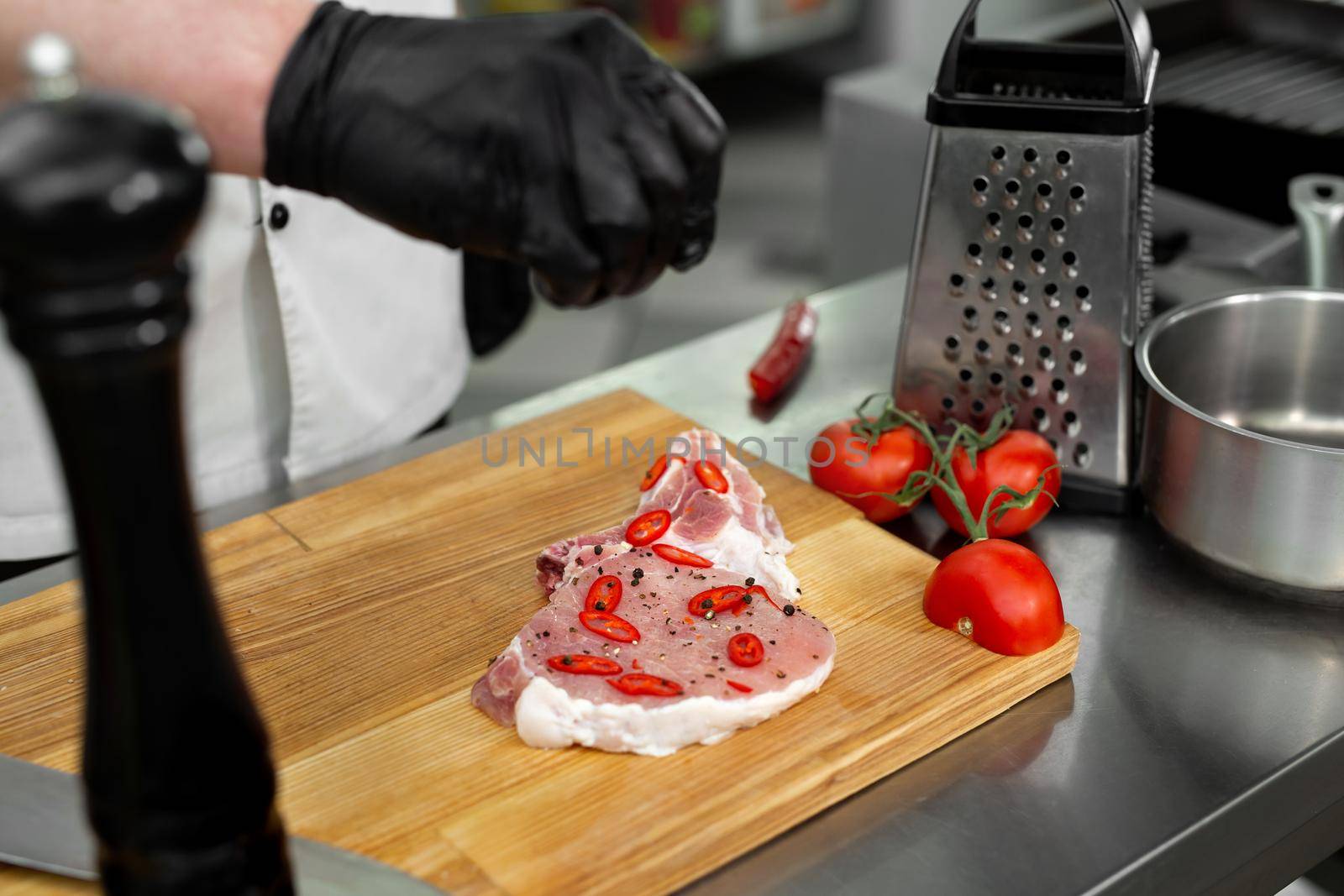 The chef adds salt with his hands and marinates the raw meat before grilling it. Restaurant service food concept.