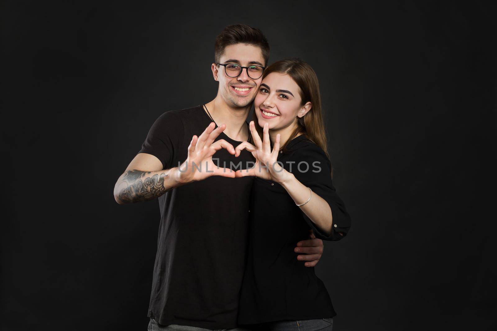 Happy couple in love showing heart with their fingers. Closeup of couple making heart shape with hands by StudioPeace