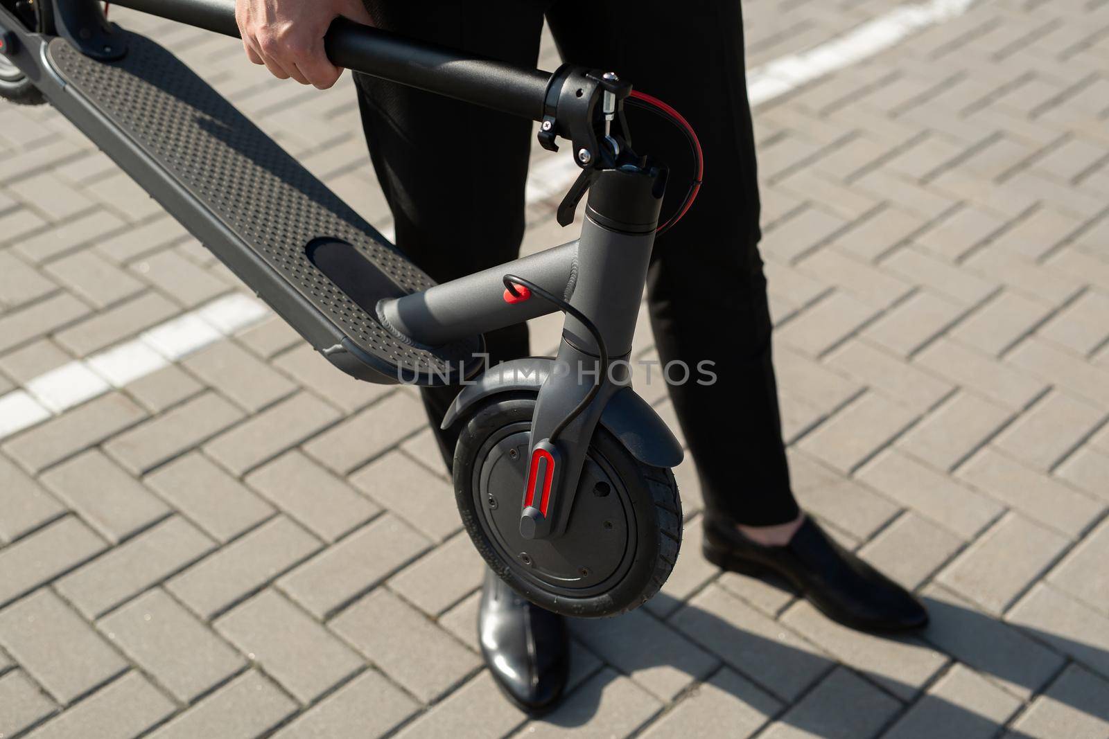 Close-up of a businessman's hands with an electric scooter.