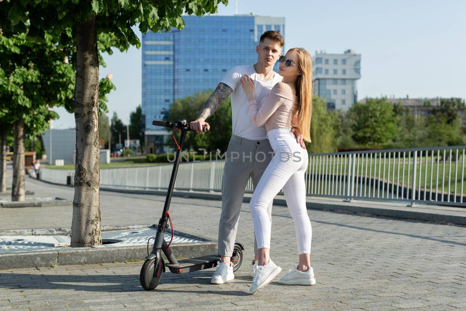 Girl and guy walk on electric scooters around the city, a couple in love on scooters by StudioPeace