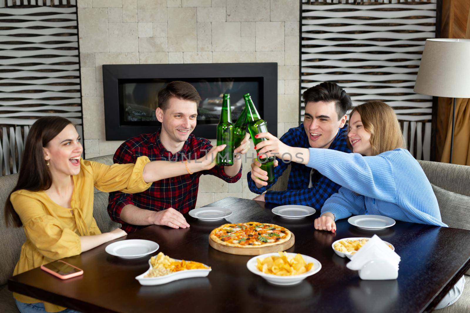 Group of young friends with pizza and bottles of drink celebrating