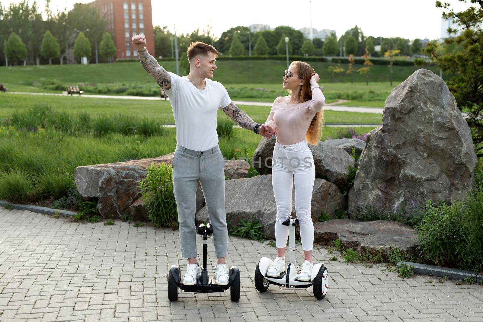 Young man and woman riding on the hoverboard in the park. by StudioPeace