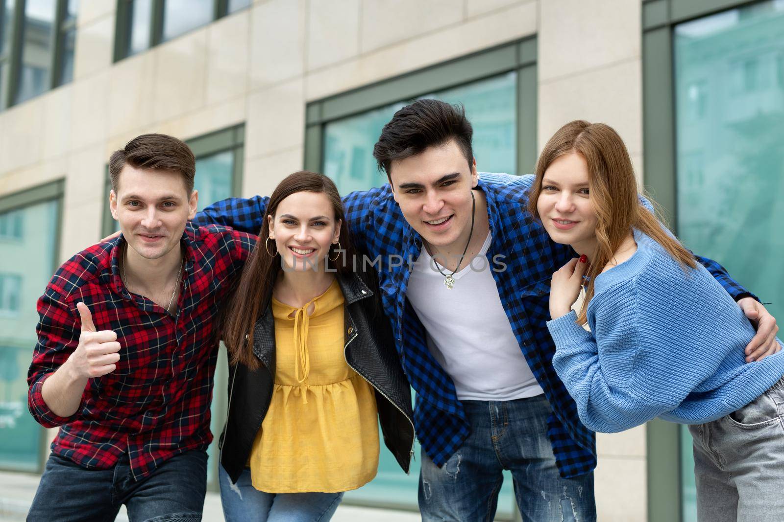 Concept of friendship, travel and recreation - a group of smiling friends hug and smile at the camera