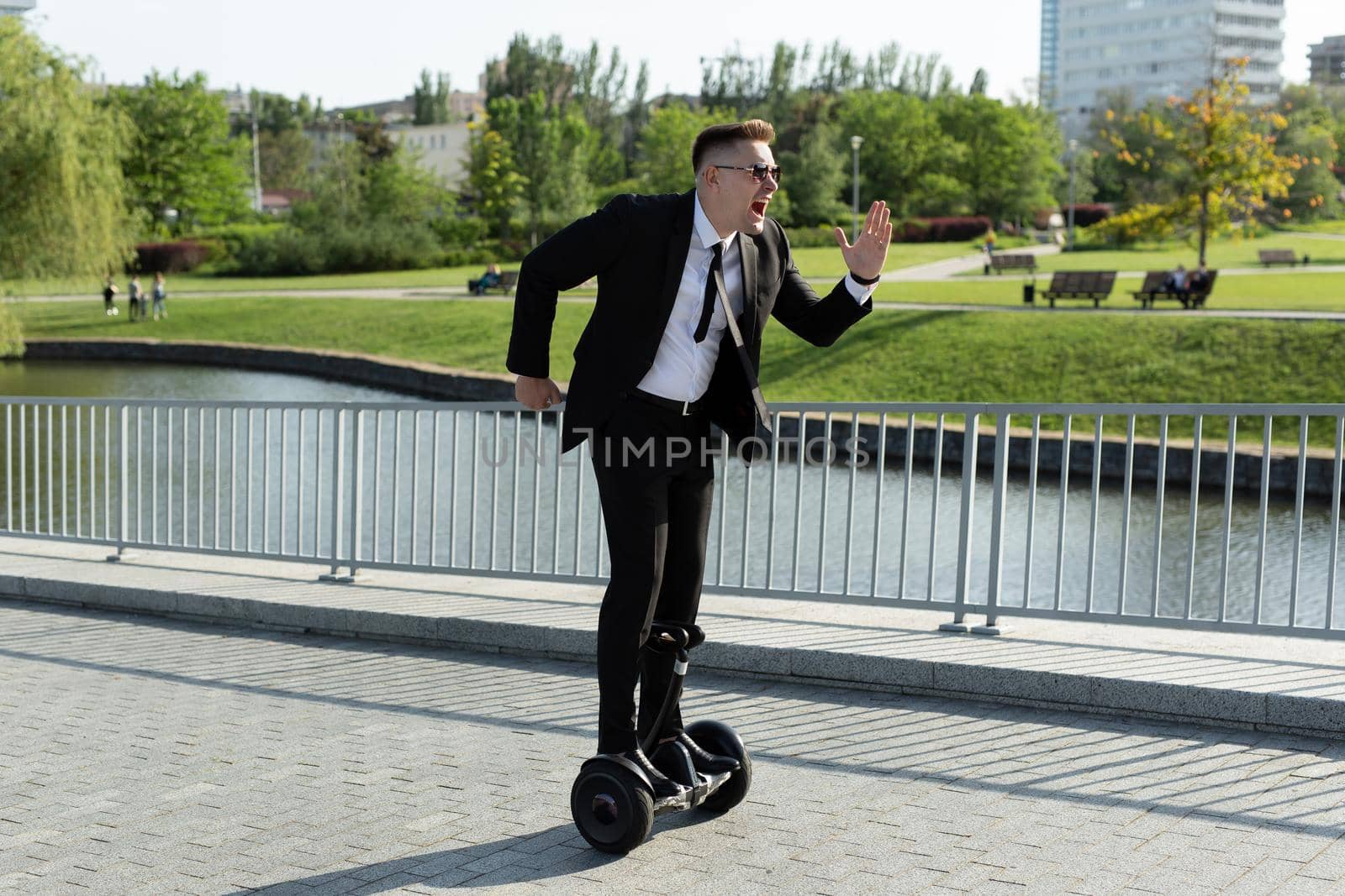 Businessman in a black suit rides a gyro scooter and has fun.