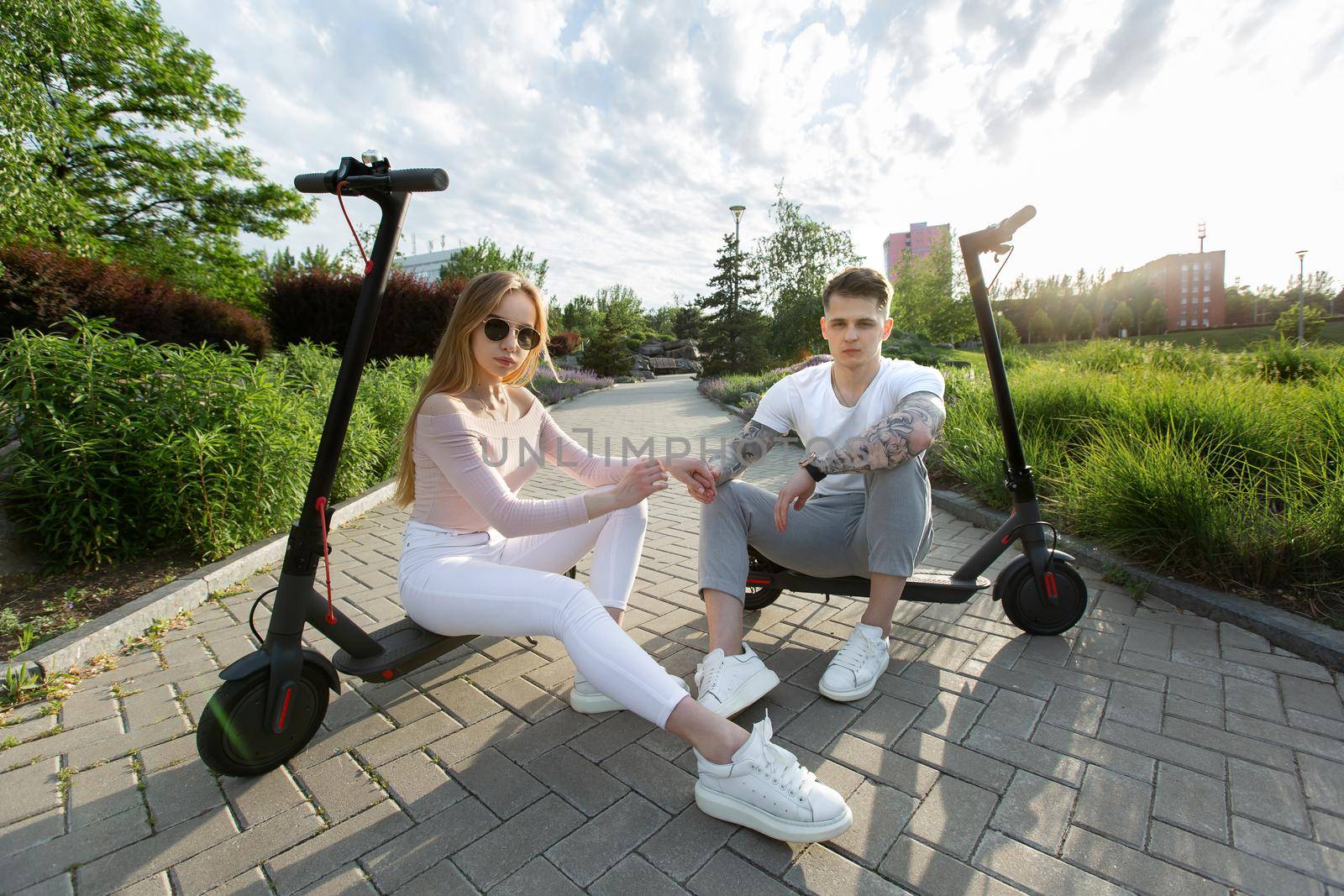Man and a woman sit on electric scooters in the park. by StudioPeace
