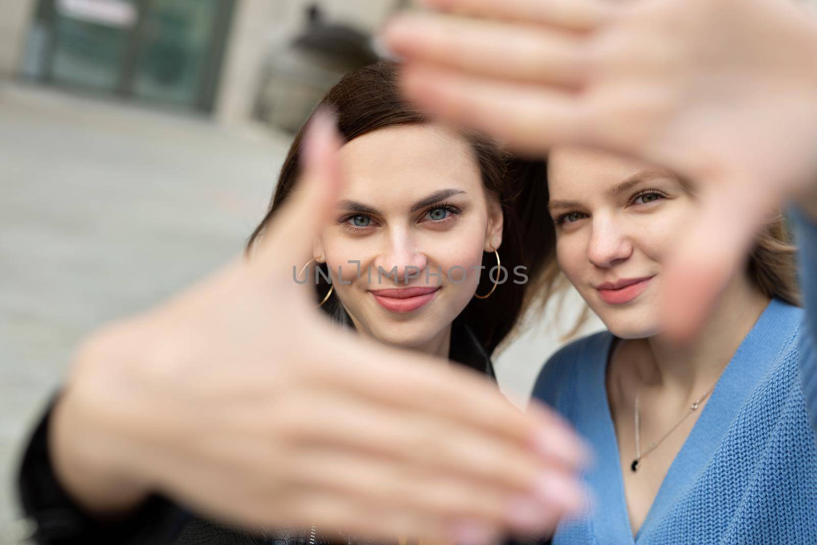 Two girls take selfies in the city. by StudioPeace