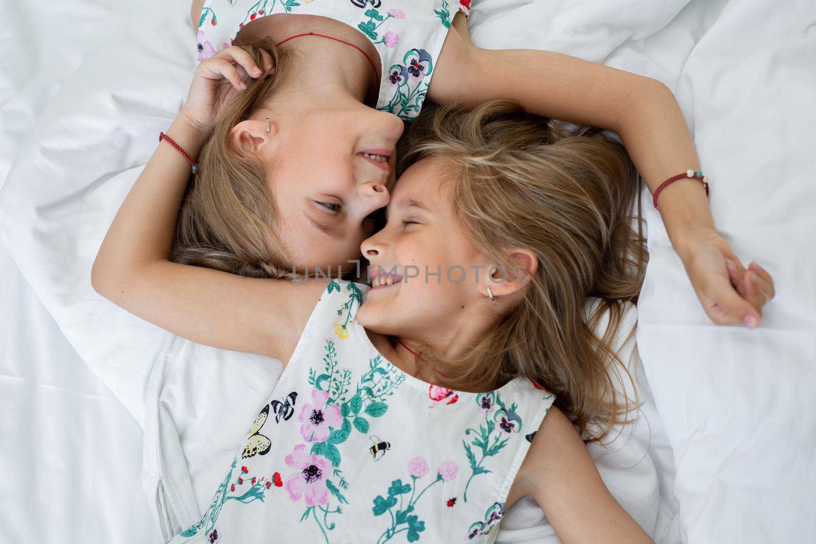 Two twin sisters are lying on the bed.