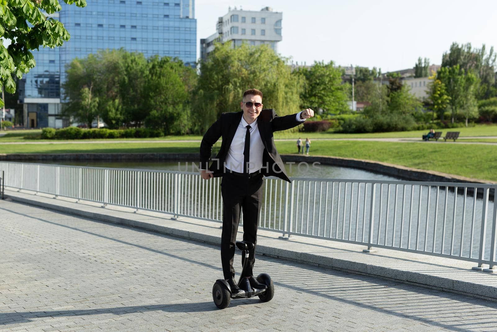 Businessman in a black suit rides a gyro scooter and has fun by StudioPeace