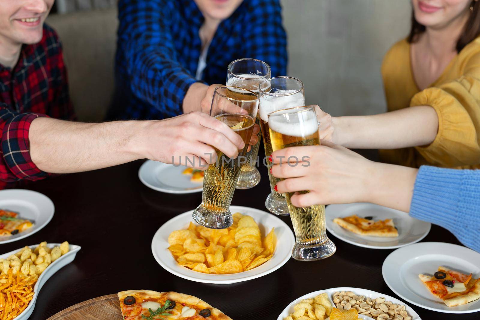 Clinking beer near pizza in bar. Friends rest and eat pizza. by StudioPeace