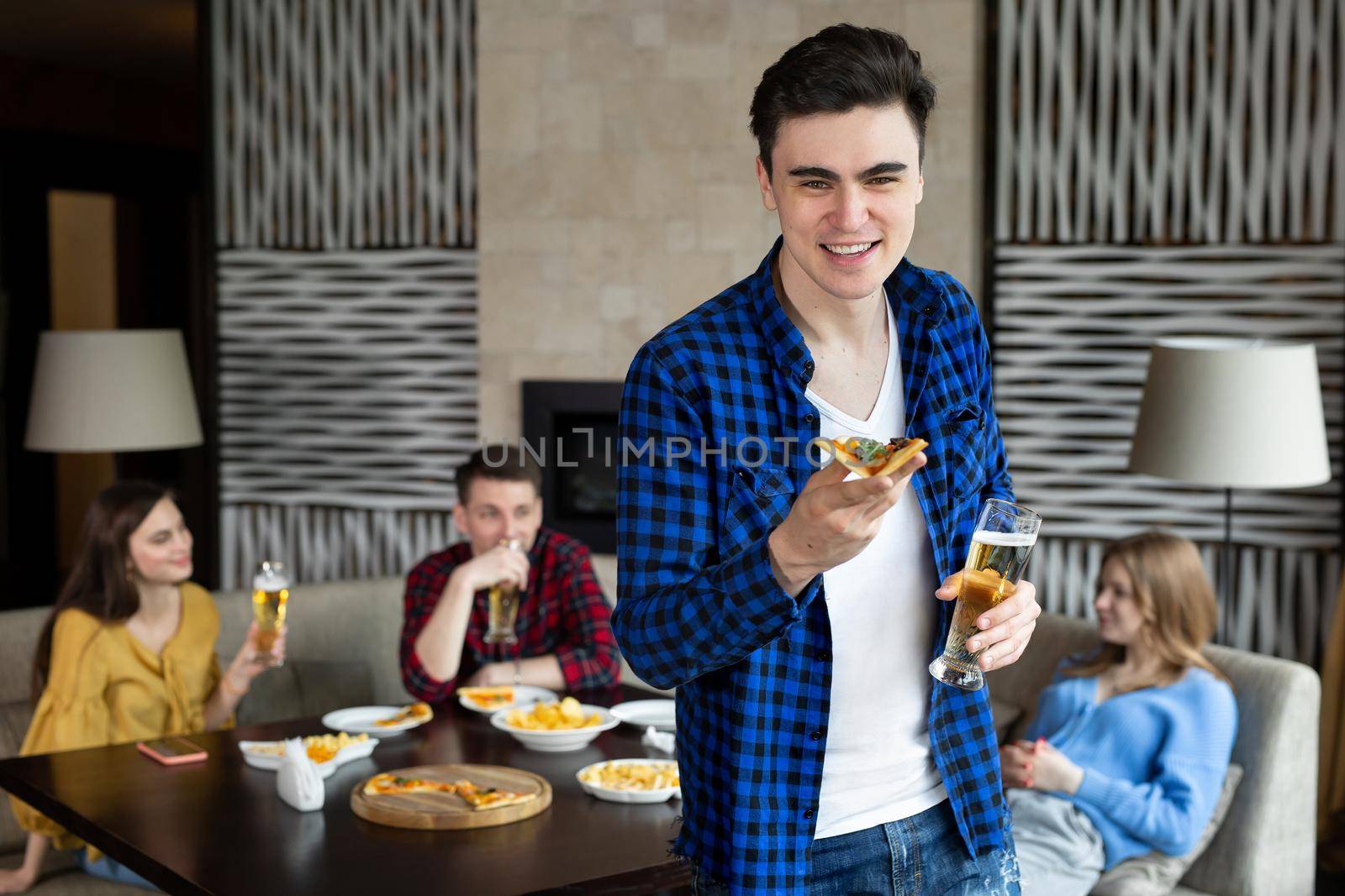 Portrait of a young man holding pizza and beer in a pub