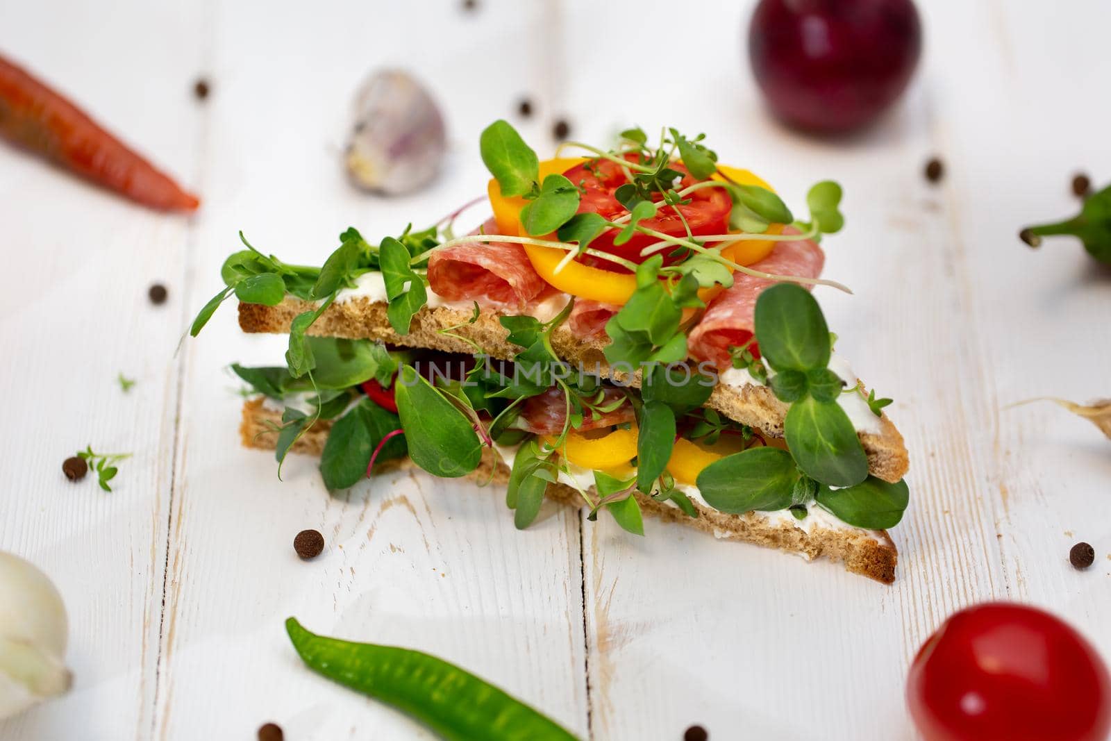 Sandwiches with sausage, cheese and micro-greens on a white background