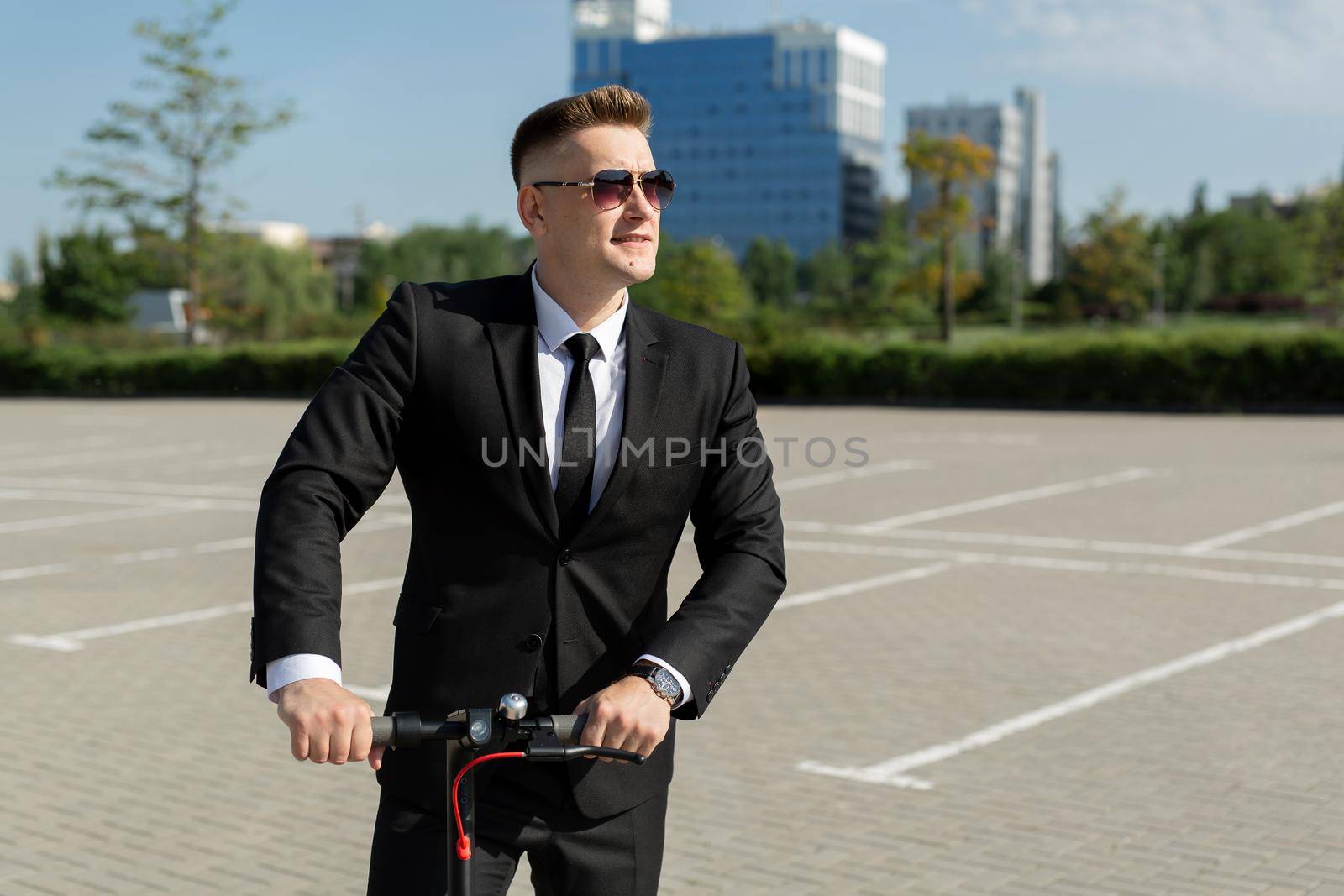 Young businessman in sunglasses on an electric scooter in the city.