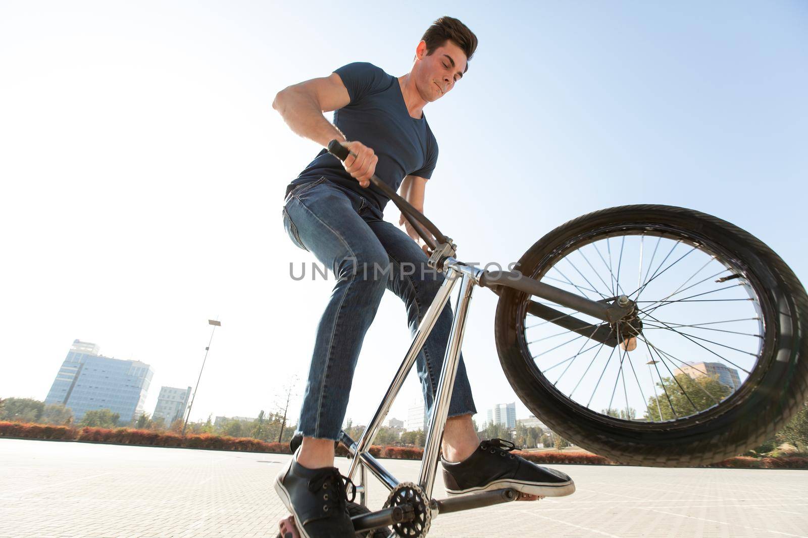 Street portrait of a bmx rider in a jump on the street in the background of the city landscape and the sun