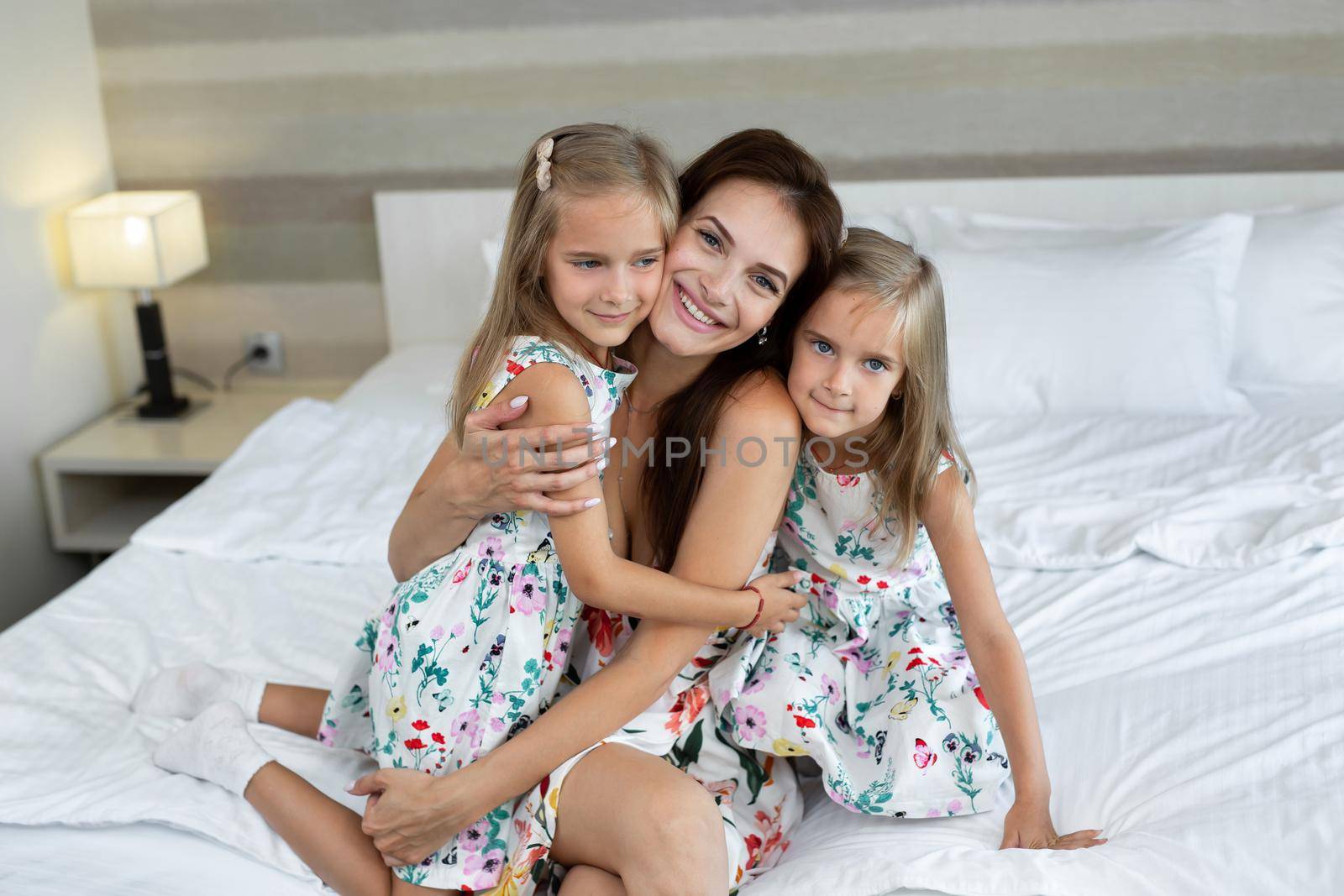 Twin girls hug their mom in a hotel room