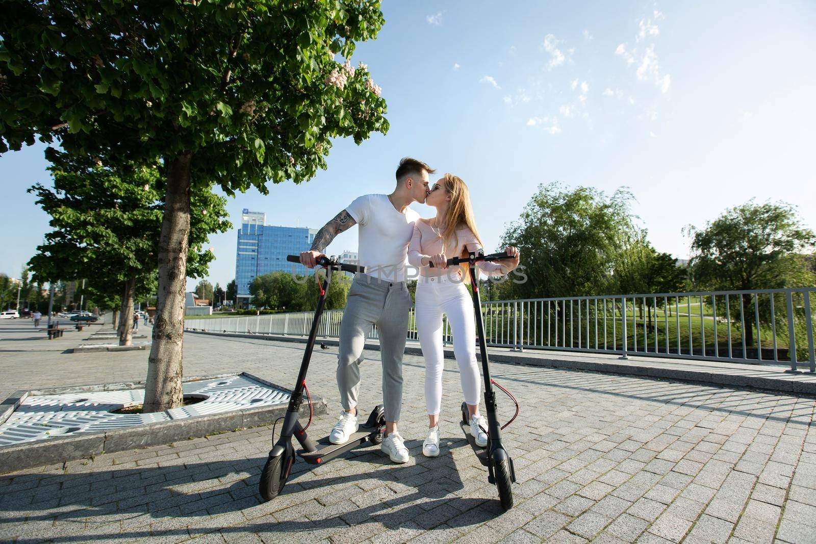 An attractive couple of lovers ride electric scooters and kiss by StudioPeace