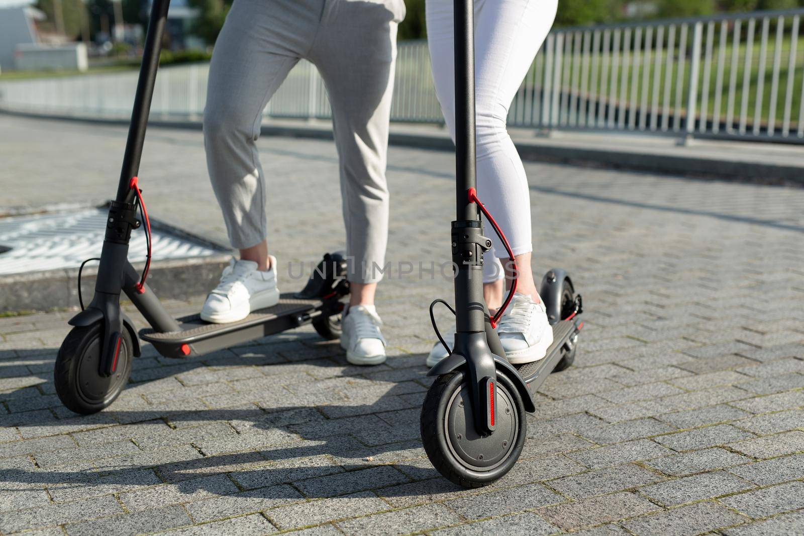 A couple of men and women are walking in the Park and standing near electric scooters by StudioPeace