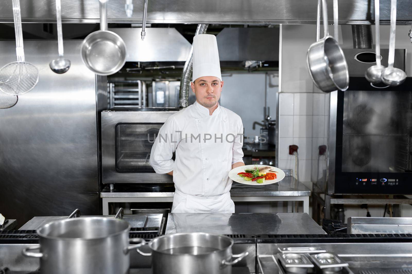 Chef in a restaurant holds a plate with a ready-made dish