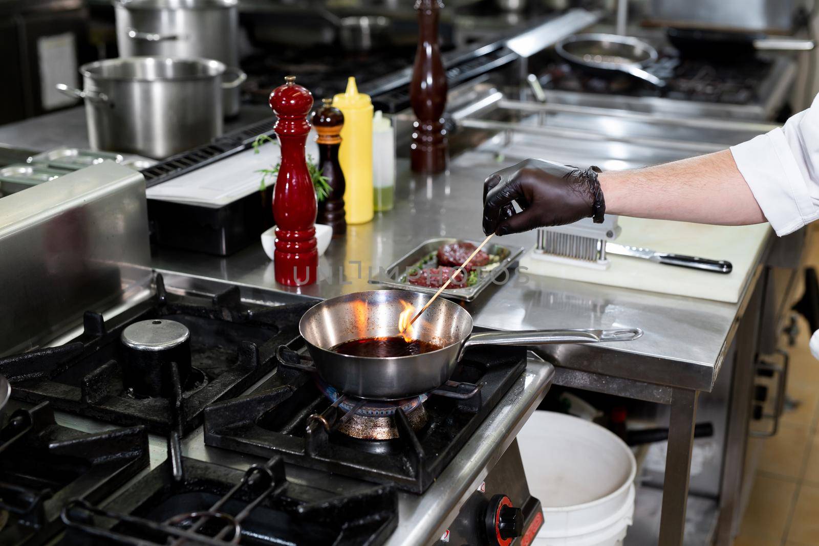 Chef prepares the sauce in a pan with red win. by StudioPeace