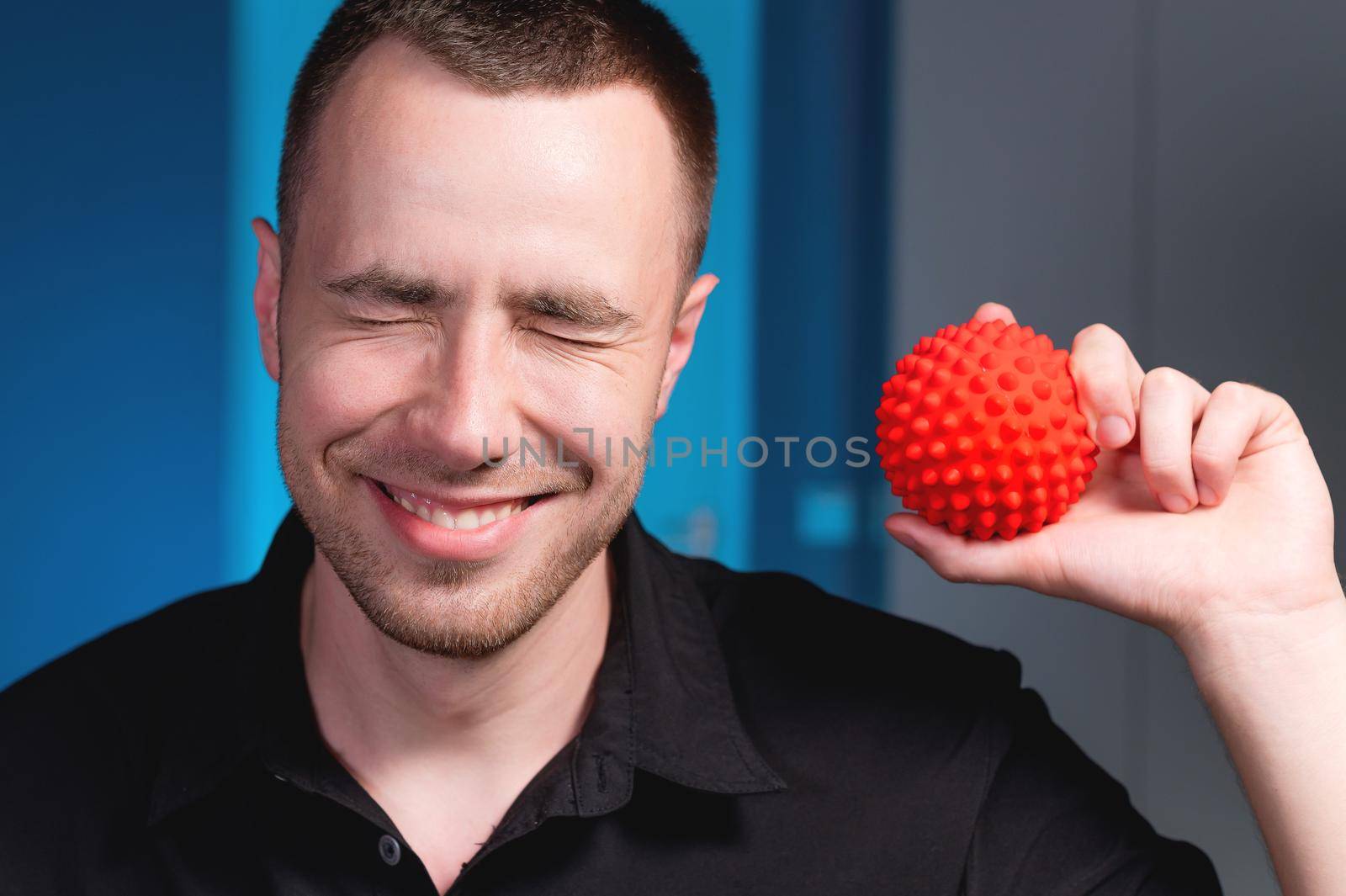 Portrait of a young caucasian doctor physiotherapist massage therapist with a massage ball in his hand. Myofascial release and massage ball copy space.