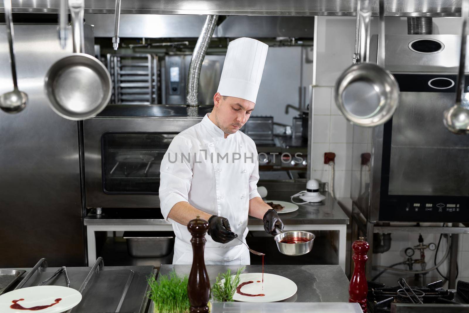 Chef pours red strawberry sauce into a plate