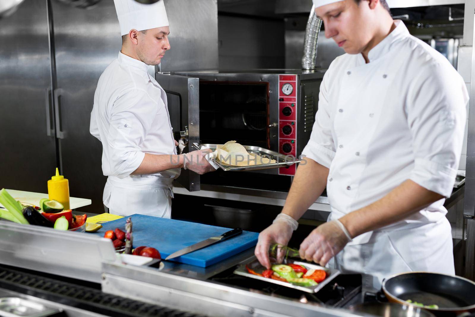 Chefs prepare delicious dishes in the kitchen by StudioPeace