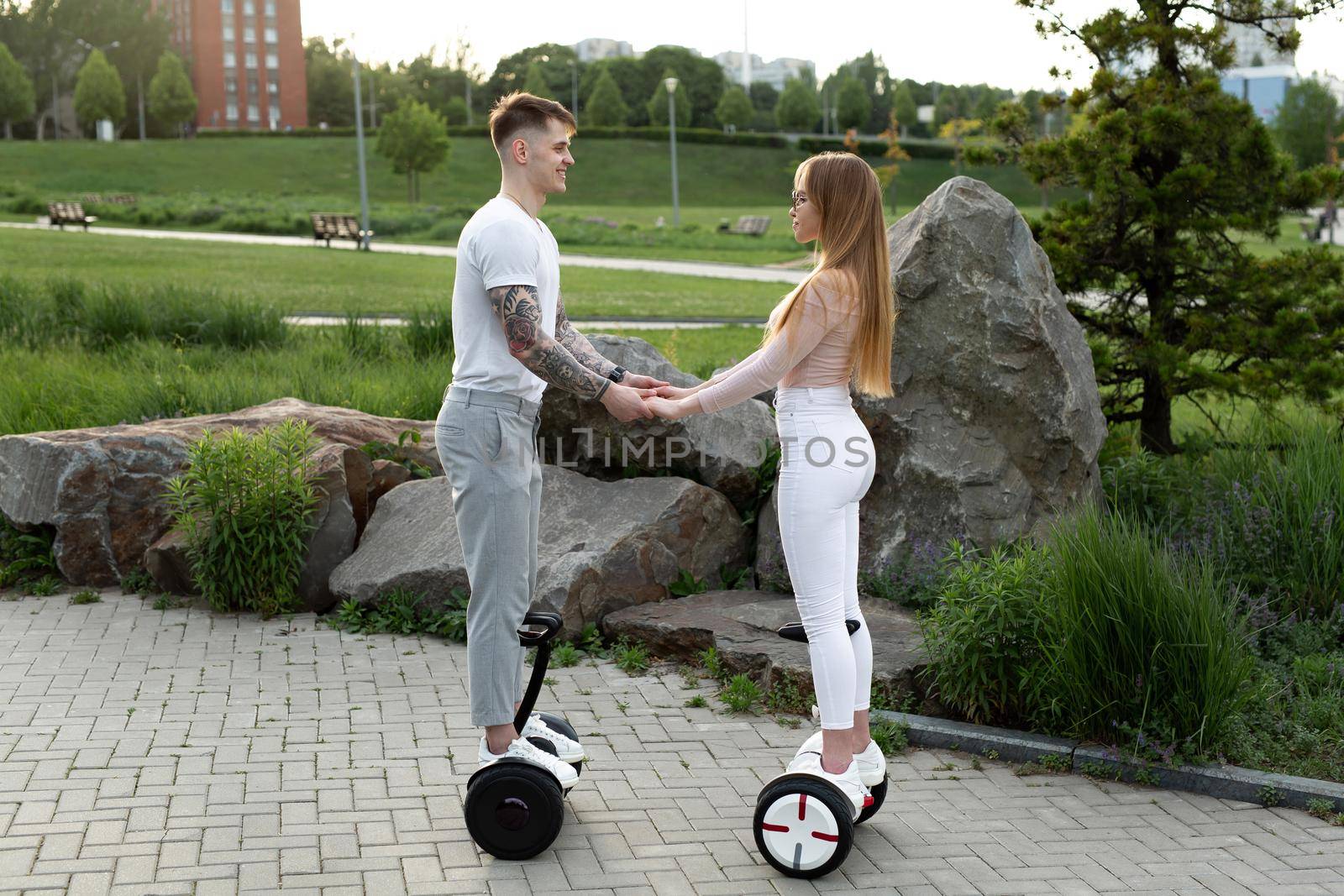Young man and woman riding on the hoverboard in the park. by StudioPeace